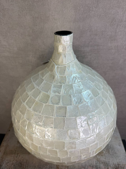 Ronde vaas met schelpmozaïek in crèmekleur, met smalle hals, geplaatst op een houten ondergrond tegen een neutrale achtergrond.