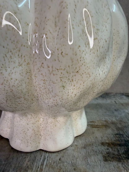 Beige keramieken vaas met organische vorm en glanzende afwerking op een houten ondergrond.