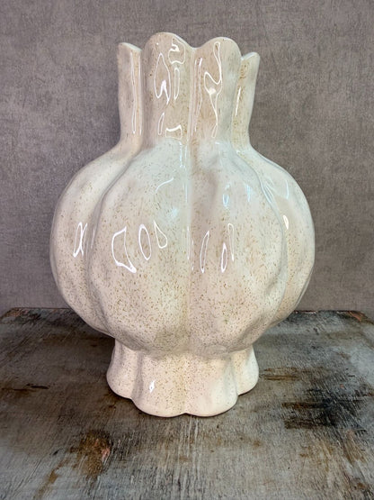 Beige keramieken vaas met organische vorm en glanzende afwerking op een houten ondergrond.