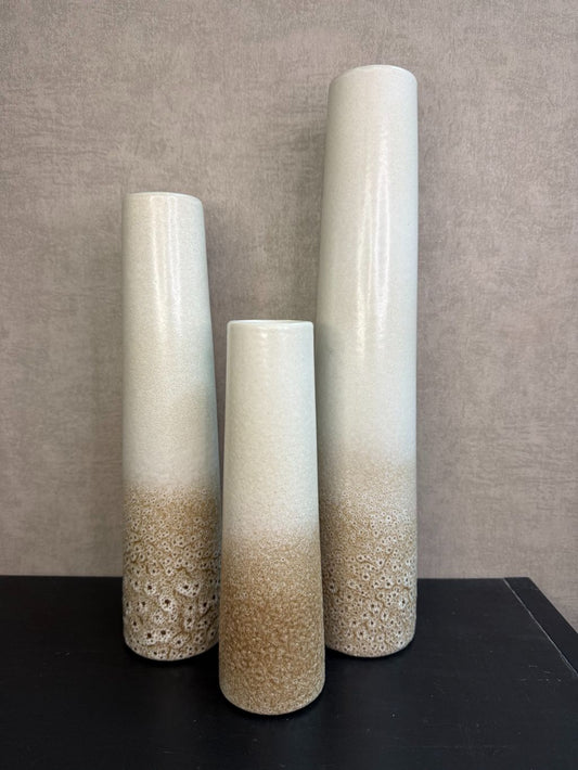 Keramieken vaas met crème-bruin kleurverloop en subtiel stippenreliëf, gepresenteerd in drie verschillende hoogtes.