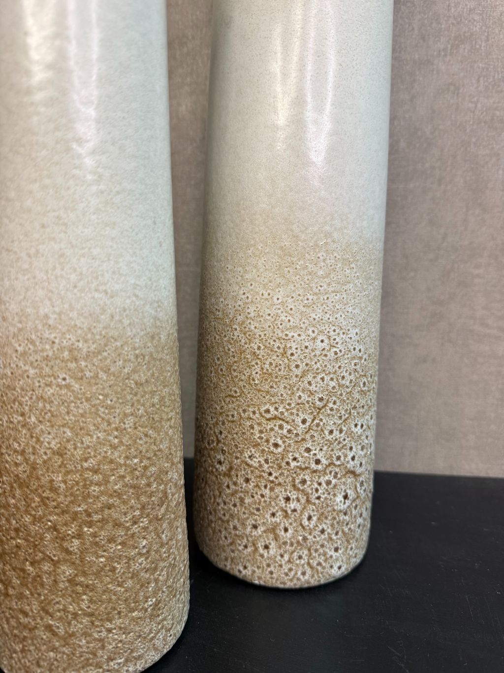 Keramieken vaas met crème-bruin kleurverloop en subtiel stippenreliëf, gepresenteerd in drie verschillende hoogtes.