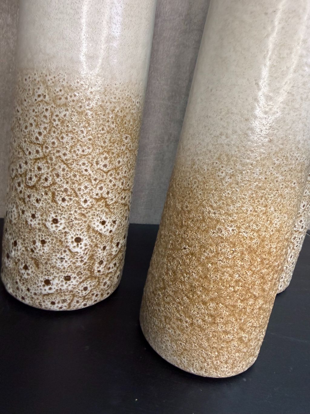 Keramieken vaas met crème-bruin kleurverloop en subtiel stippenreliëf, gepresenteerd in drie verschillende hoogtes.