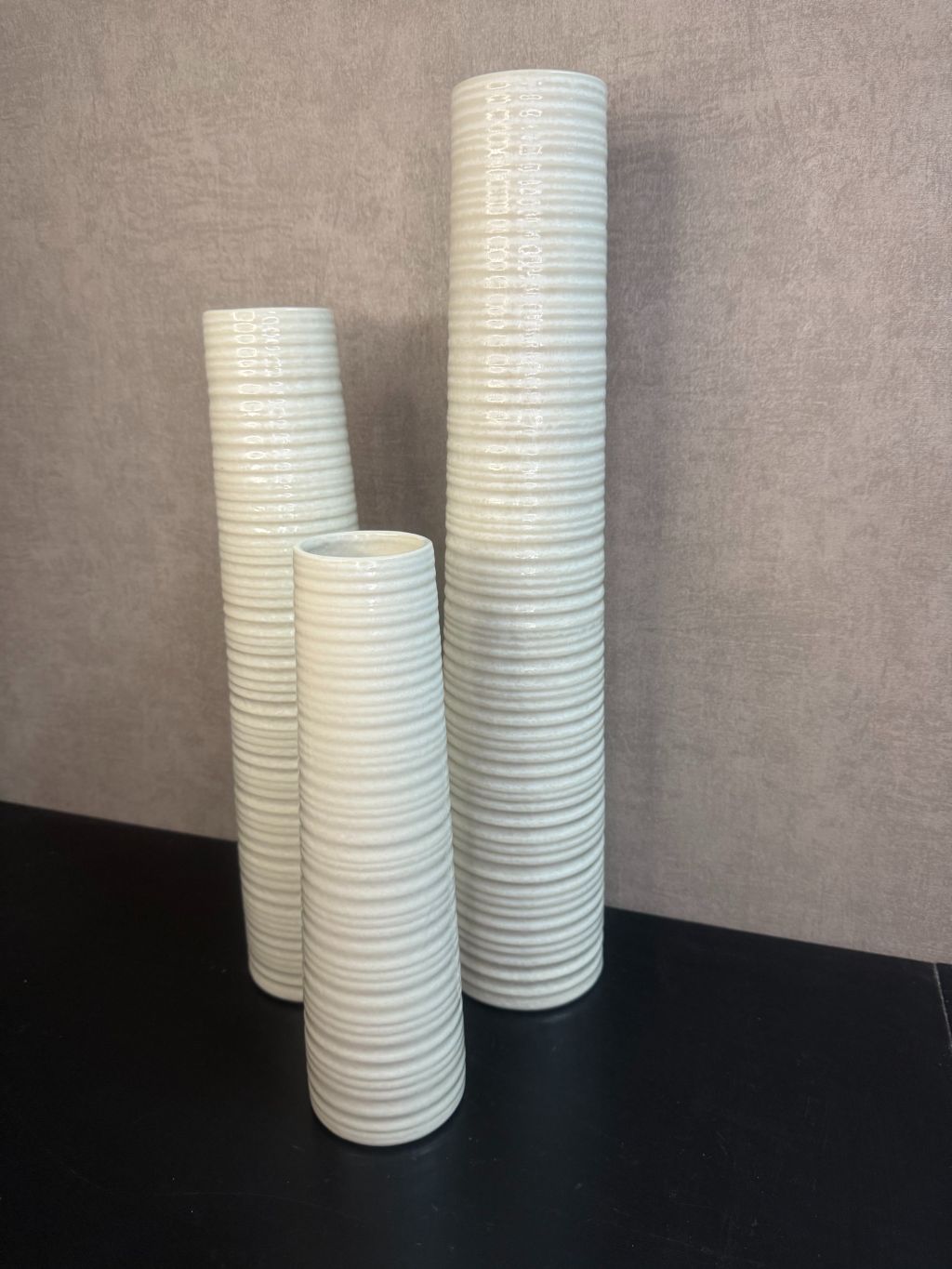 Vaas Gwinn crème – drie keramieken vazen met subtiele strepen in verschillende hoogtes tegen een grijze achtergrond.