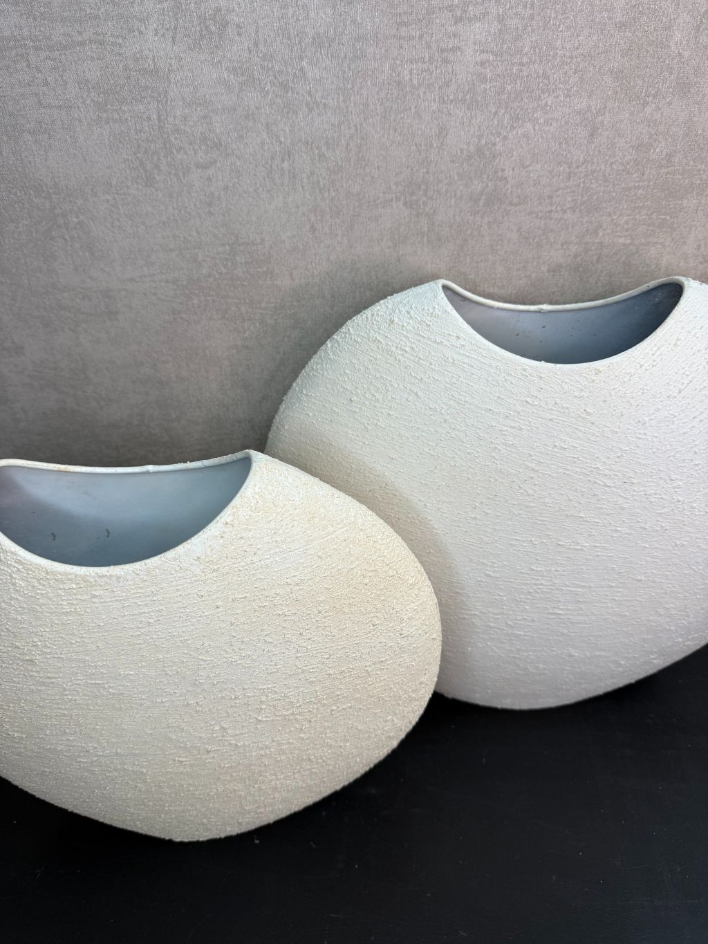 Crèmekleurige metalen vaas Ibbo met organische ronde vorm, getoond in twee formaten met subtiele tintverschillen.