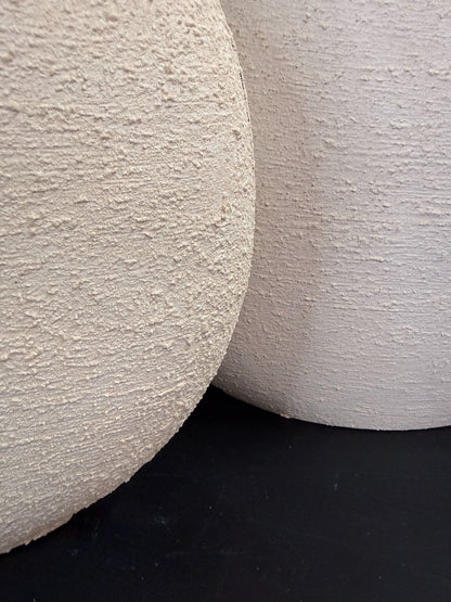 Crèmekleurige metalen vaas Ibbo met organische ronde vorm, getoond in twee formaten met subtiele tintverschillen.