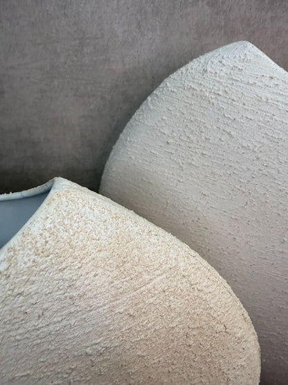 Crèmekleurige metalen vaas Ibbo met organische ronde vorm, getoond in twee formaten met subtiele tintverschillen.