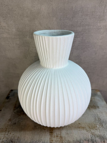 Witte keramieken vaas Jill met ronde vorm en verticaal ribbelpatroon op een houten ondergrond tegen een neutrale achtergrond.