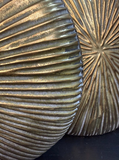 Goudkleurige metalen vaas Libera met rond, plat design en reliëfstructuur, getoond in twee formaten op een donkere ondergrond.