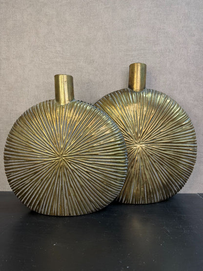 Goudkleurige metalen vaas Libera met rond, plat design en reliëfstructuur, getoond in twee formaten op een donkere ondergrond.