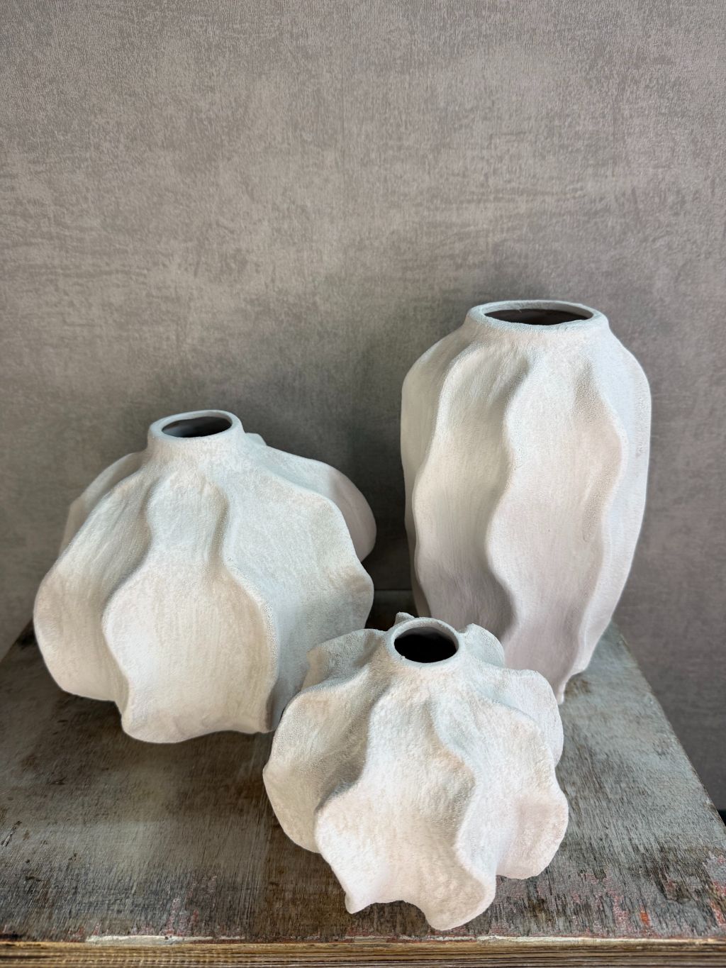 Handgemaakte witte keramieken vaas Lisboa in drie formaten met organische vorm, stijlvol opgesteld op een houten ondergrond.