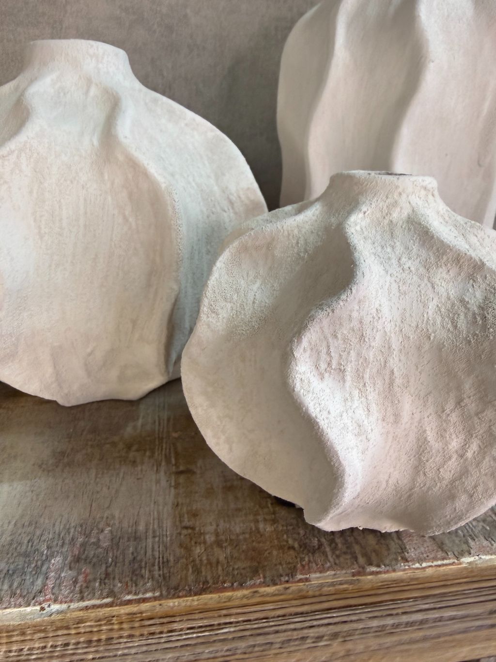 Handgemaakte witte keramieken vaas Lisboa in drie formaten met organische vorm, stijlvol opgesteld op een houten ondergrond.