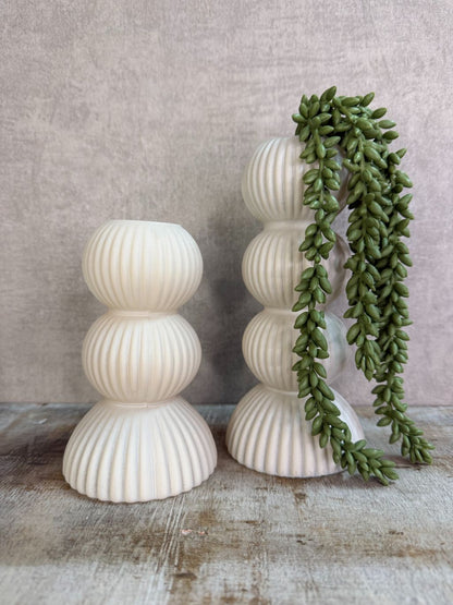 Crèmekleurige glazen vaas met ribbelstructuur en gestapelde vorm, geschikt voor bloemen, gefotografeerd op een houten ondergrond. met een kunst erwtenplantje.