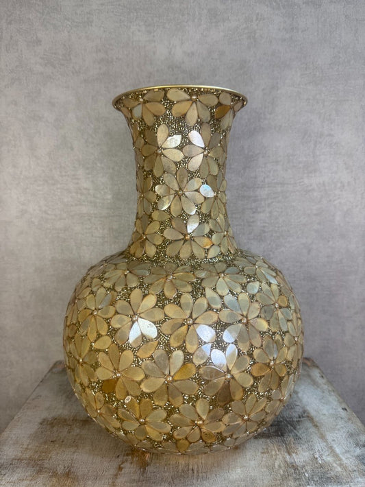 Gouden bolvormige vaas met bloemmotief van metaal en glas op een houten ondergrond.