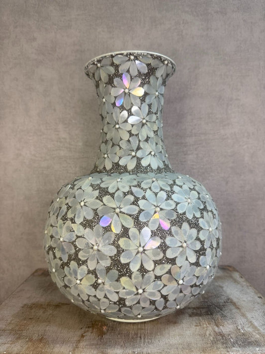 Bolvormige zilveren vaas met bloemmotief van metaal en glas op een houten ondergrond.