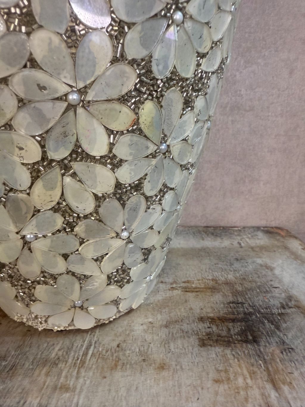 Smalle zilveren vaas met bloemmotief van metaal en glas op een houten ondergrond.