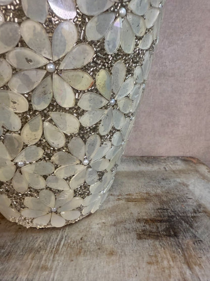 Smalle zilveren vaas met bloemmotief van metaal en glas op een houten ondergrond.