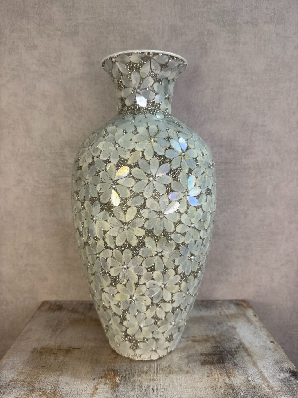 Smalle zilveren vaas met bloemmotief van metaal en glas op een houten ondergrond.