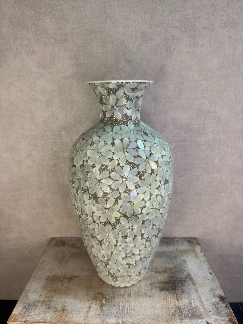 Smalle zilveren vaas met bloemmotief van metaal en glas op een houten ondergrond.