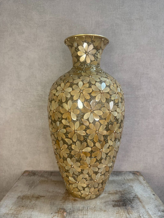 Gouden smalle vaas met bloemmotief van metaal en glas op een houten ondergrond.