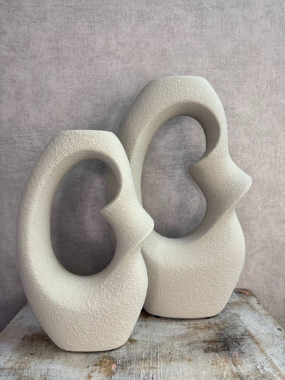 Set van twee beige keramieken vazen met organische open vorm in verschillende formaten op een houten ondergrond.