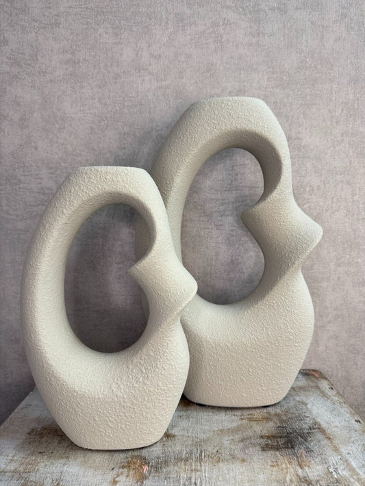 Set van twee beige keramieken vazen met organische open vorm in verschillende formaten op een houten ondergrond.