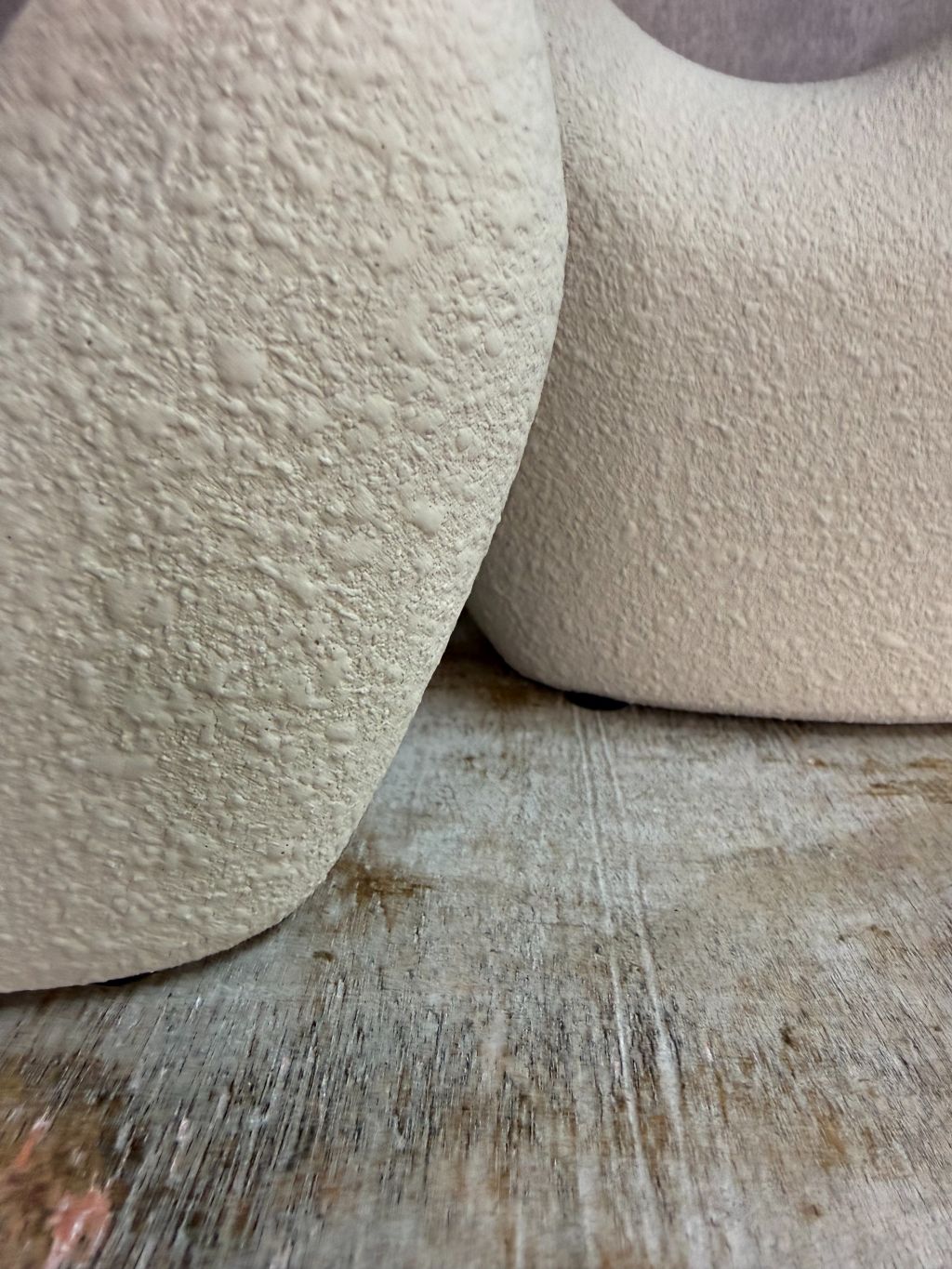 Set van twee beige keramieken vazen met organische open vorm in verschillende formaten op een houten ondergrond.