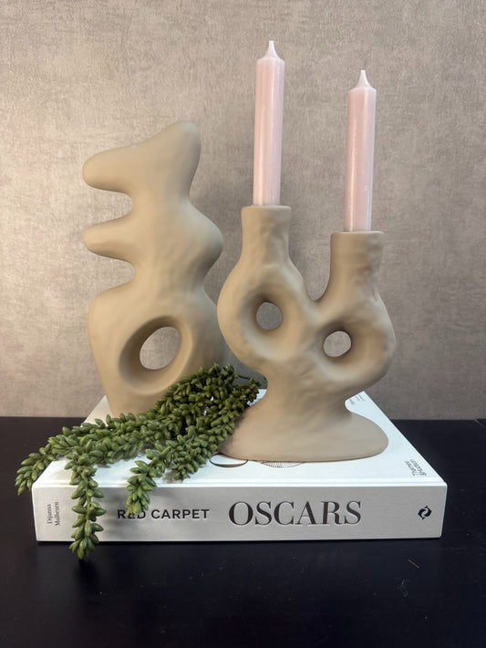 Vakkenkast decoratieset met beige ornament en kandelaar met nude kaarsen op tafelboek Oscars, afgewerkt met een groen erwtenplantje.