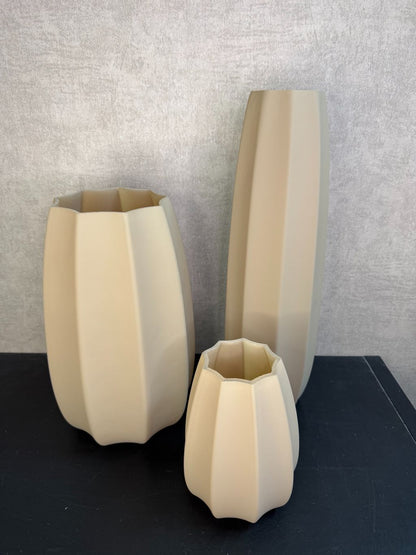 Bruine glazen vaas met facetvormig design in drie verschillende hoogtes, geplaatst op een donkere ondergrond.