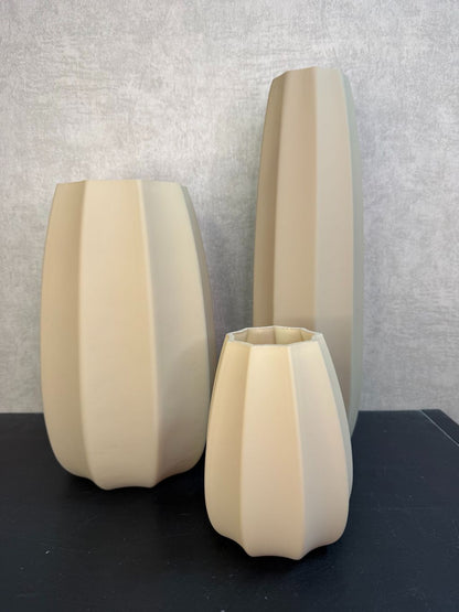 Bruine glazen vaas met facetvormig design in drie verschillende hoogtes, geplaatst op een donkere ondergrond.