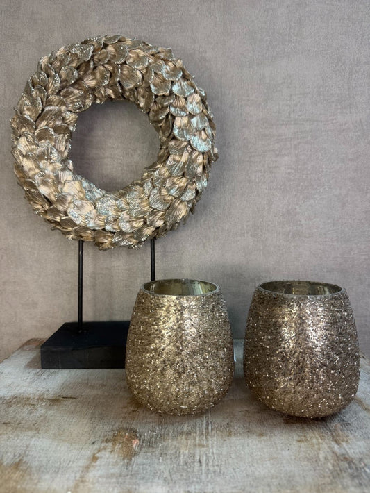 Taupe-champagne decoratieset met bladornament op standaard en twee glinsterende waxinelichthouders op houten ondergrond.