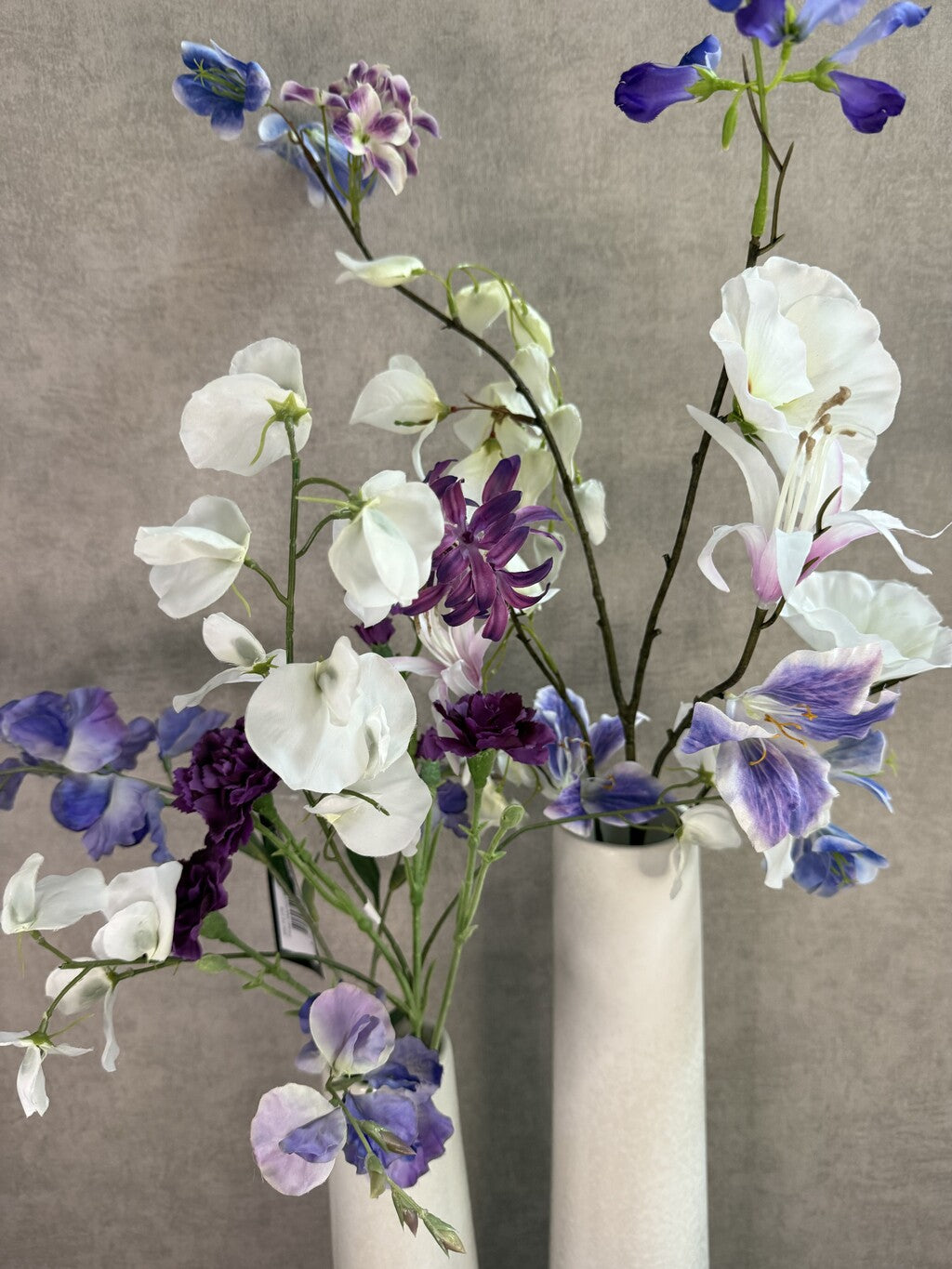Vensterbank decoratie set Gwen met twee witte keramieken vazen en bloemen in wit, paars en blauw.