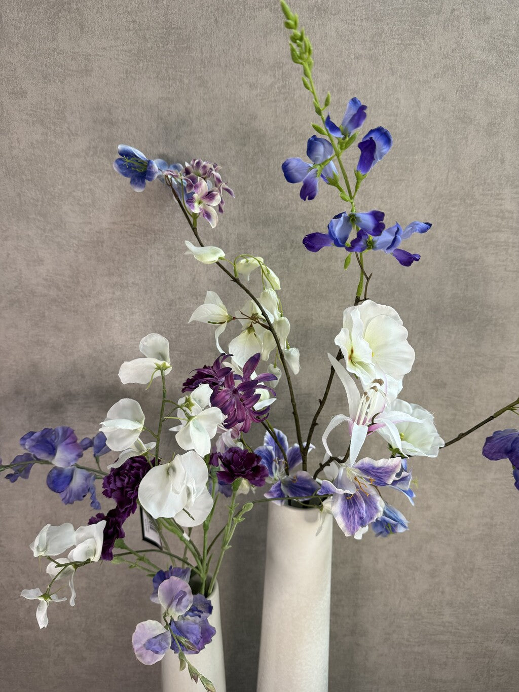 Vensterbank decoratie set Gwen met twee witte keramieken vazen en bloemen in wit, paars en blauw.