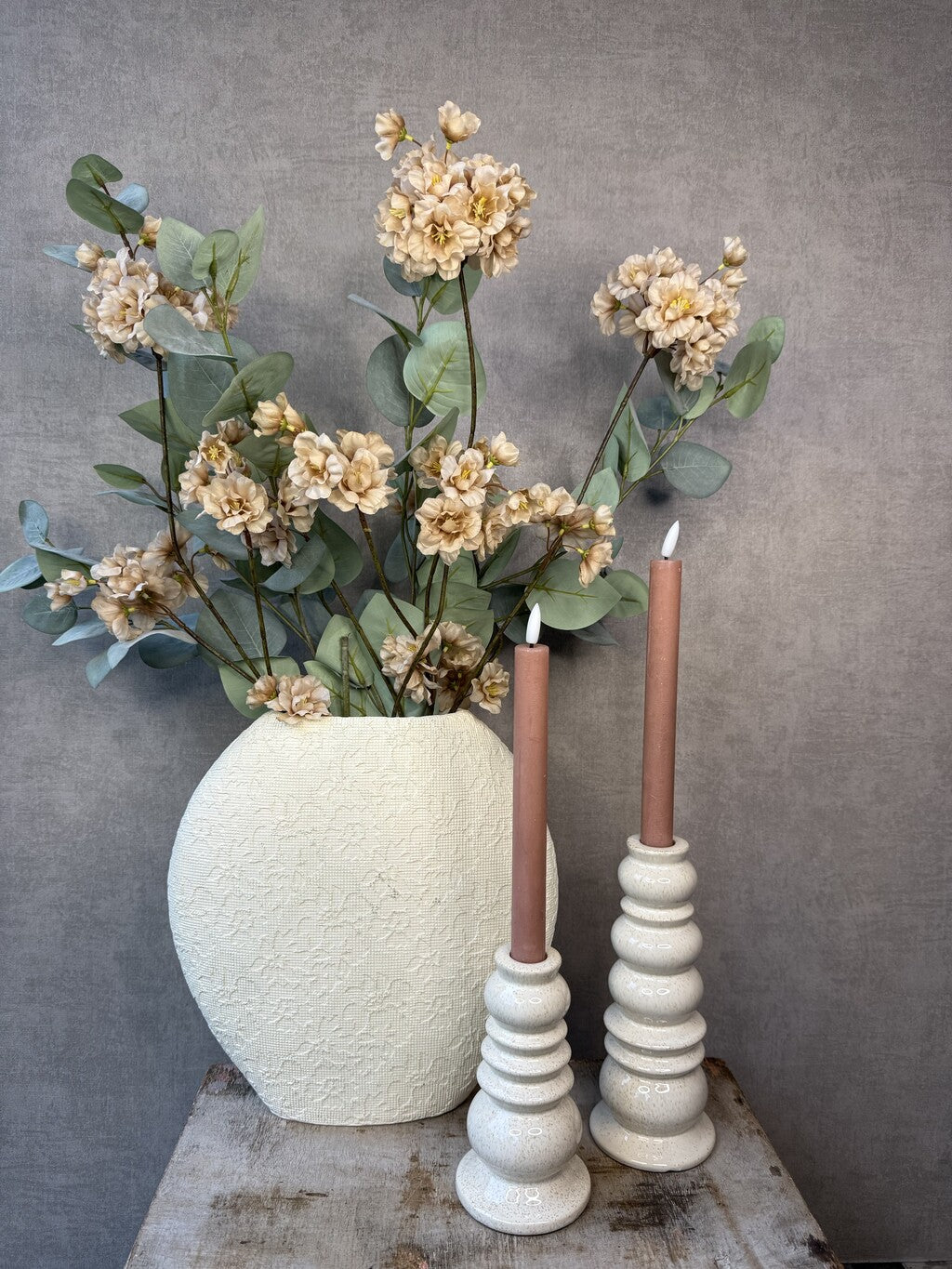Vensterbank decoratie set Rena met beige vaas, roze kunstbloemen, groene takken en twee beige kandelaars.