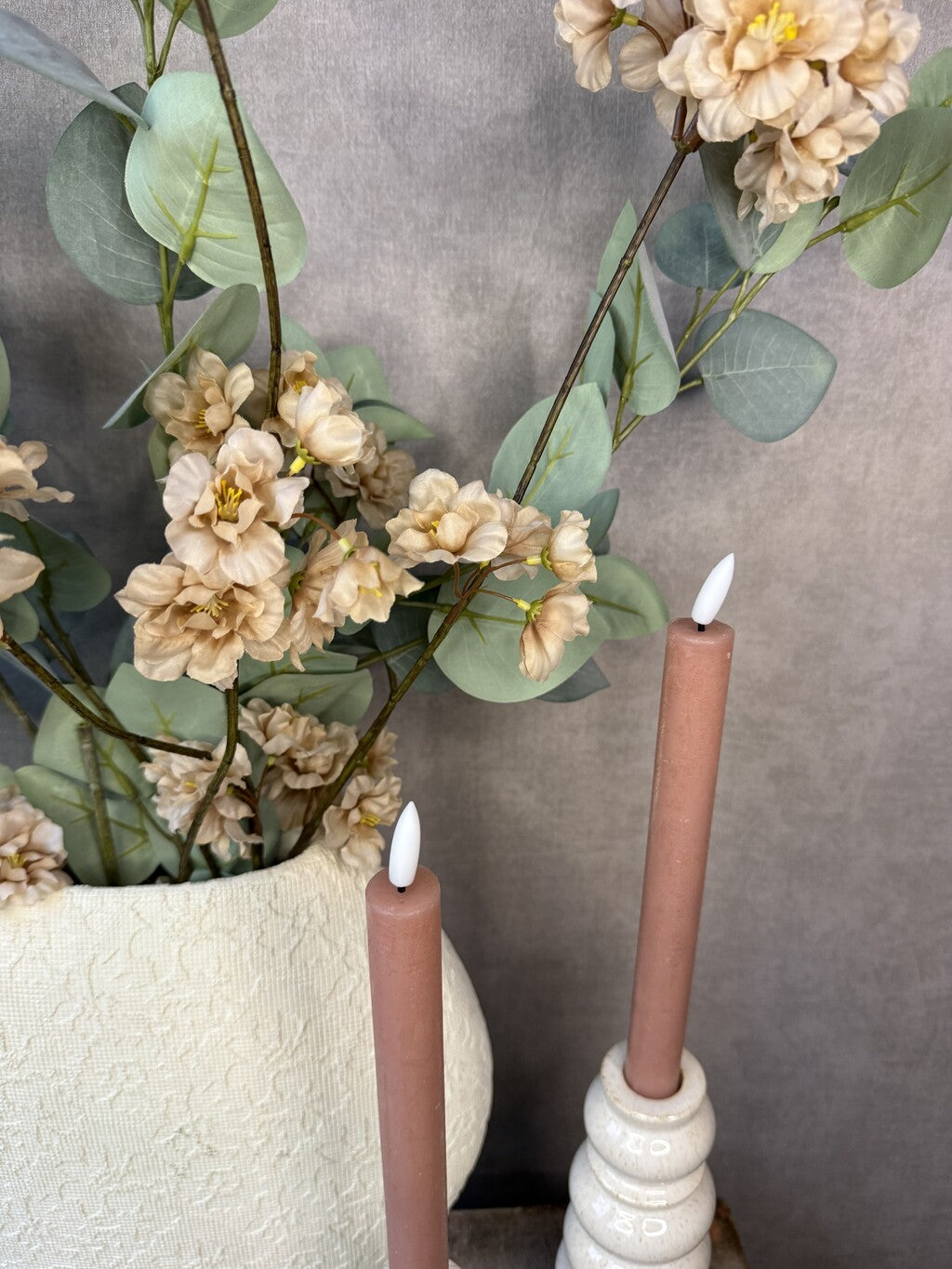 Vensterbank decoratie set Rena met beige vaas, roze kunstbloemen, groene takken en twee beige kandelaars.
