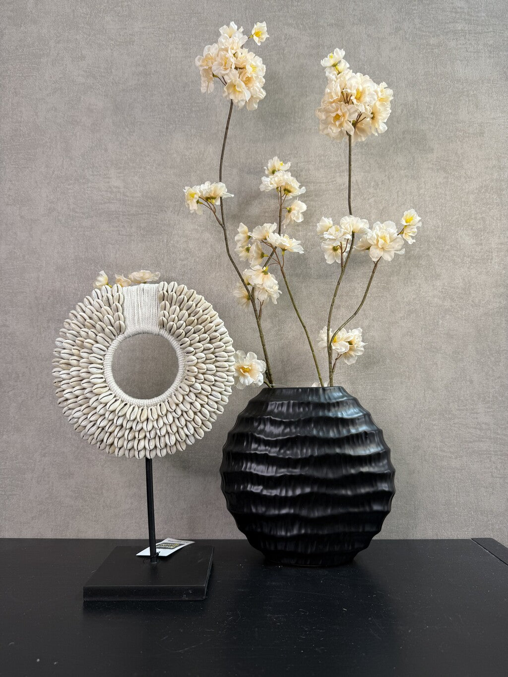 Vensterbank decoratie set Shelly met zwarte vaas, crème bloemen en rond schelpenornament op standaard.