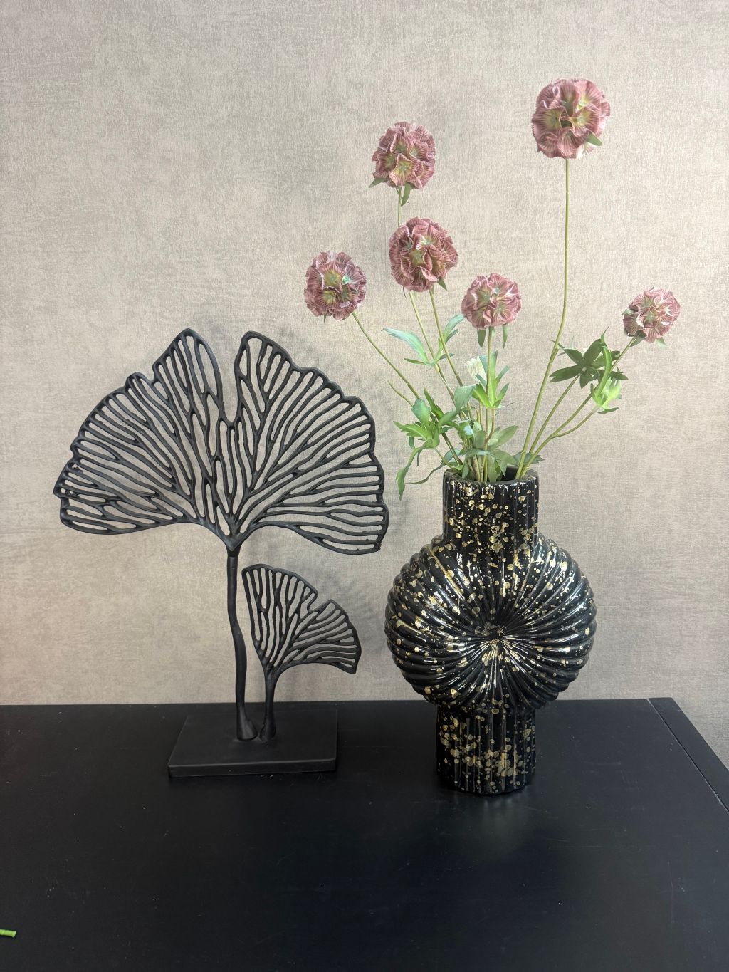 Vensterbank decoratieset met zwarte vaas met goudspikkels, oudroze kunstbloemen en zwart metalen ginkgo-ornament.