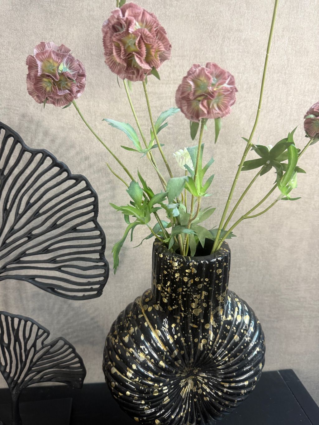 Vensterbank decoratieset met zwarte vaas met goudspikkels, oudroze kunstbloemen en zwart metalen ginkgo-ornament.