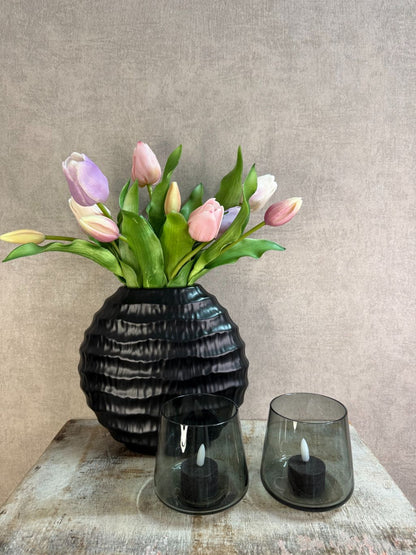 Vensterbank decoratieset met pastelkleurige real touch tulpen in een zwarte vaas en twee zwarte LED waxinelichtjes op een houten ondergrond.