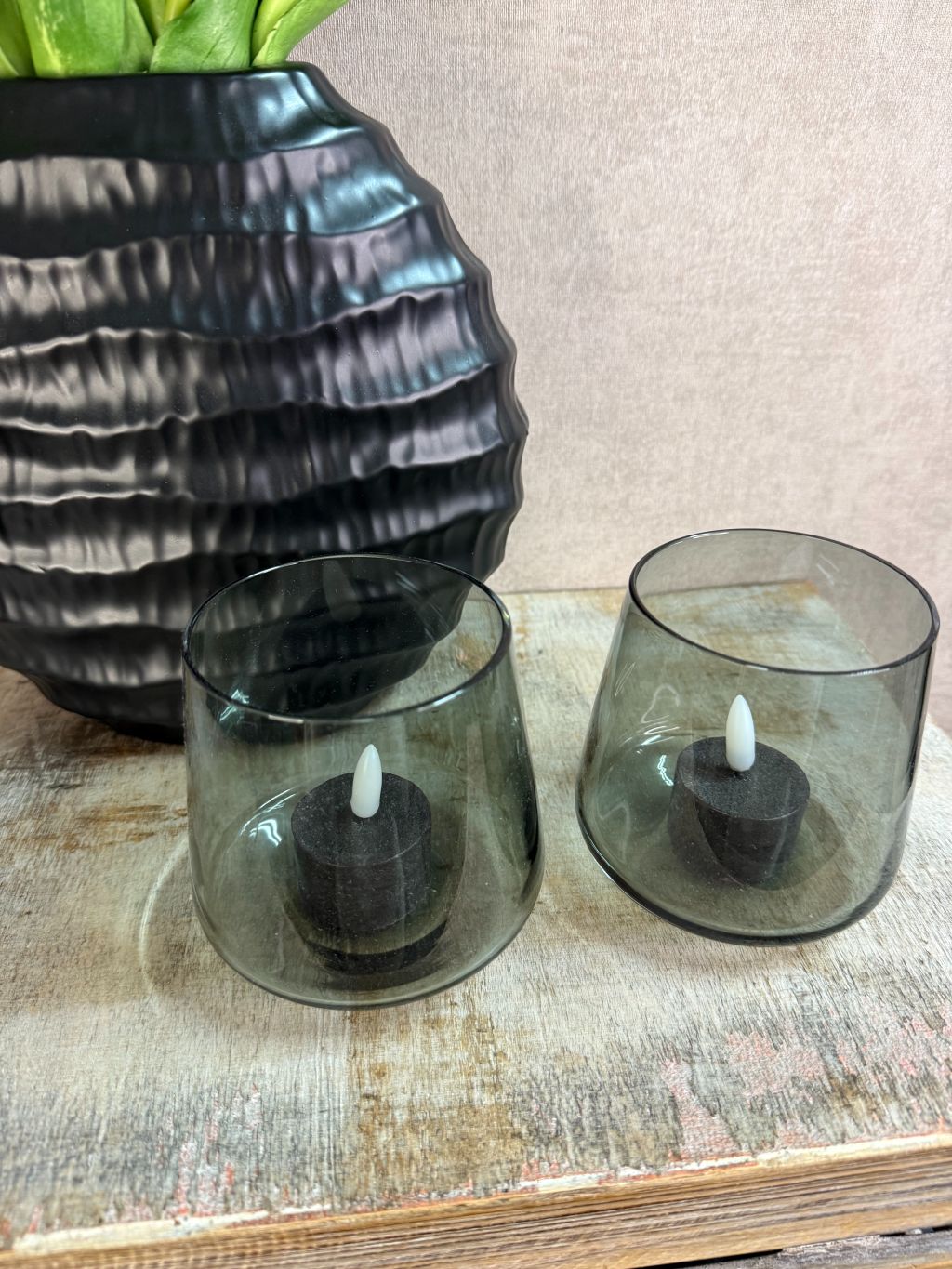 Vensterbank decoratieset met pastelkleurige real touch tulpen in een zwarte vaas en twee zwarte LED waxinelichtjes op een houten ondergrond.