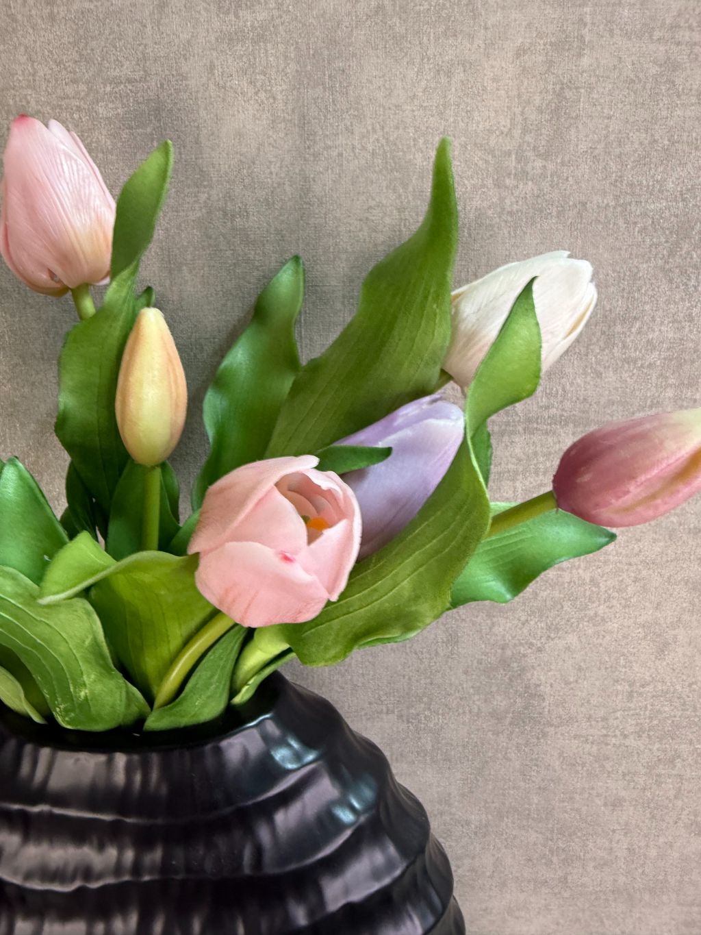 Vensterbank decoratieset met pastelkleurige real touch tulpen in een zwarte vaas en twee zwarte LED waxinelichtjes op een houten ondergrond.