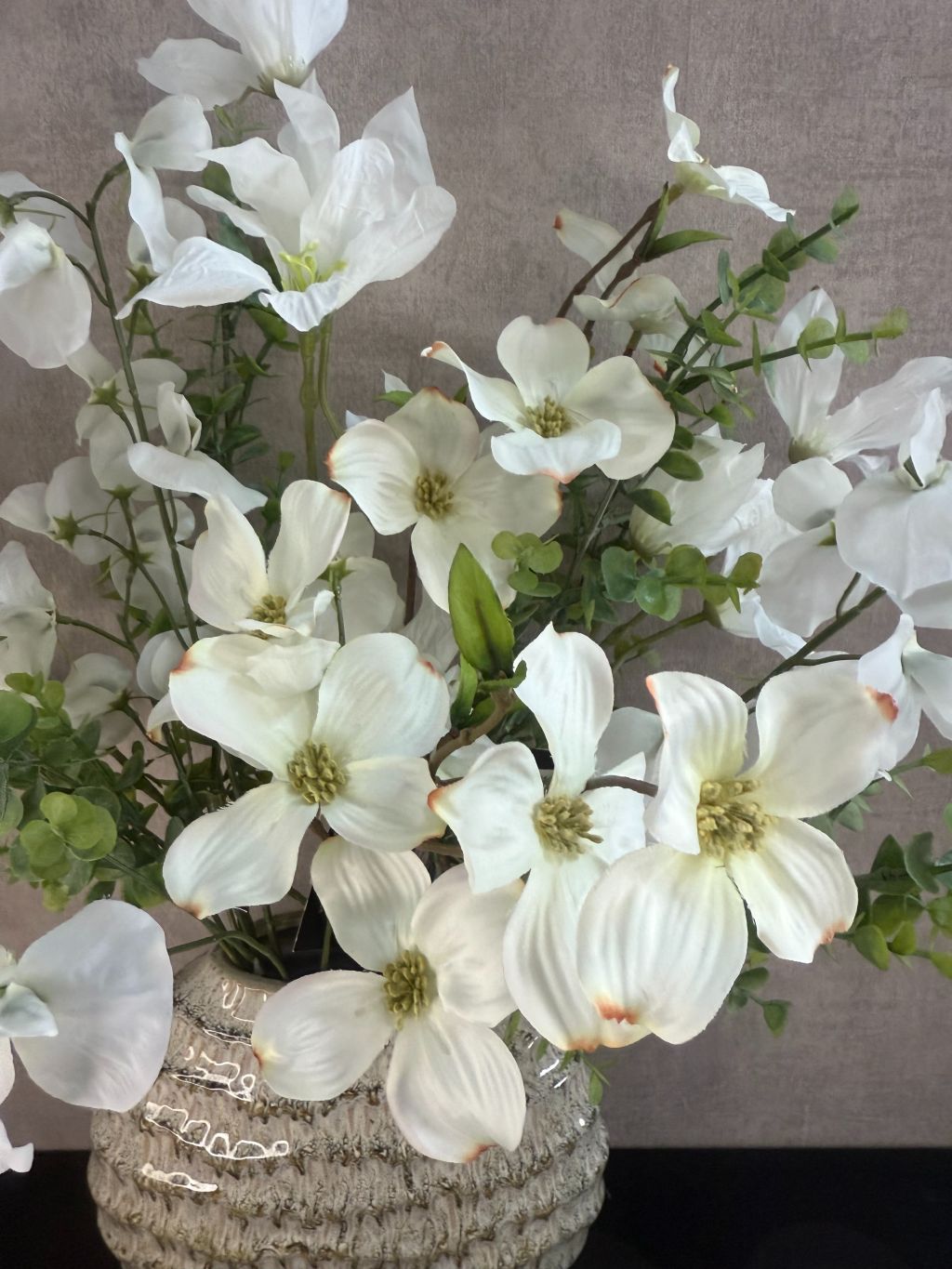 Vensterbank decoratieset met groene vaas gevuld met witte kunstbloemen en twee witte waxinelichthouders, op een zwarte ondergrond.