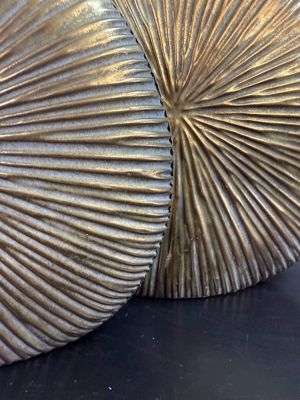 Twee goudkleurige decoratieve vazen met witte bloesemtakken op een zwarte ondergrond tegen een neutrale achtergrond.