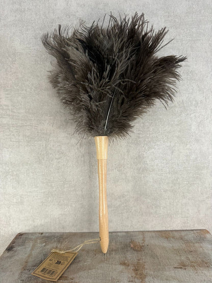 Veren plumeau met houten handgreep en bruine veren op houten ondergrond, geschikt voor het schoonmaken van delicate decoratie.
