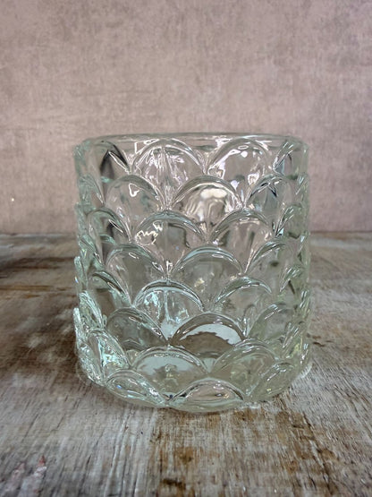 Transparante glazen waxinelichthouder Sculp met reliëfpatroon, geplaatst op een houten ondergrond.