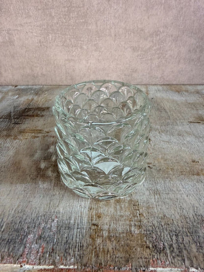 Transparante glazen waxinelichthouder Sculp met reliëfpatroon, geplaatst op een houten ondergrond.