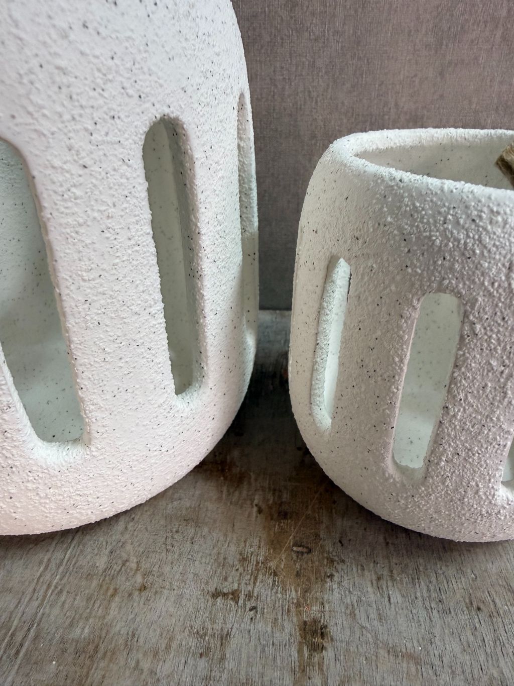 Twee witte keramieken waxinelichthouders Tobi in klein en groot formaat met opengewerkt patroon, geplaatst op een houten ondergrond.