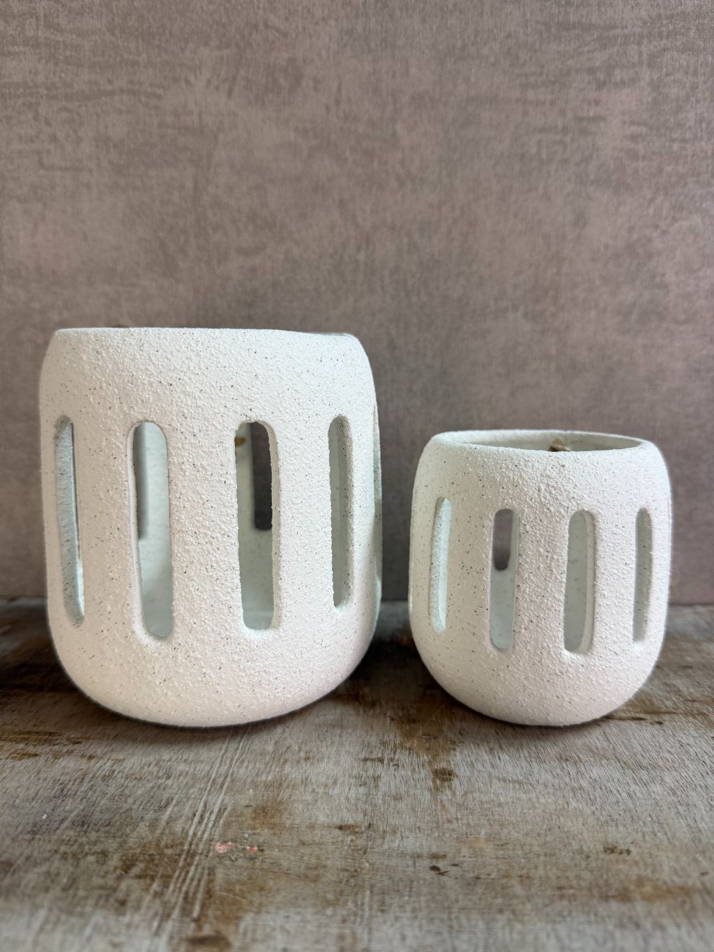 Twee witte keramieken waxinelichthouders Tobi in klein en groot formaat met opengewerkt patroon, geplaatst op een houten ondergrond.