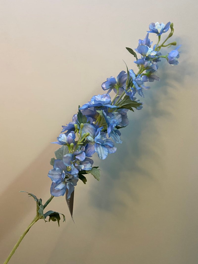  Zijden delphinium-blauwe bloem, delicaat en levendig blauw, in decoratieve opstelling.