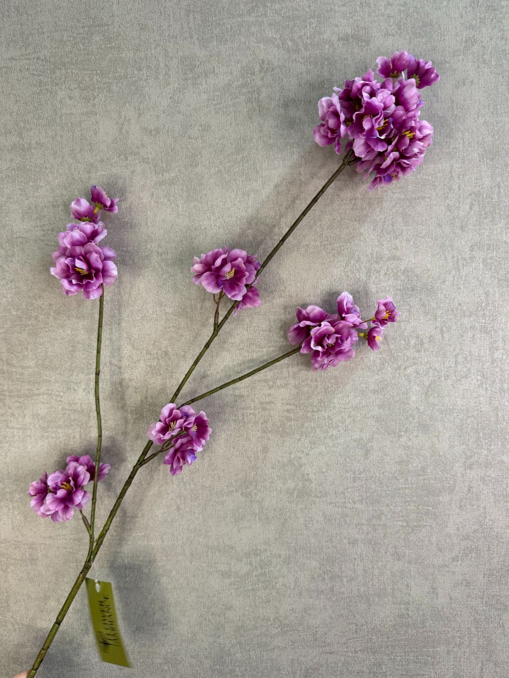 Zijden bloesemtak Prunus met paarse bloesems, slanke vertakking en een natuurlijke uitstraling tegen een neutrale achtergrond.
