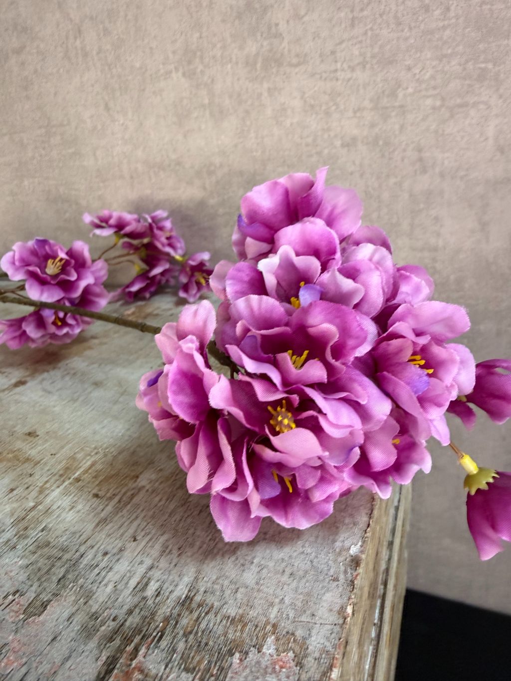 Zijden bloesemtak Prunus met paarse bloesems, slanke vertakking en een natuurlijke uitstraling tegen een neutrale achtergrond.